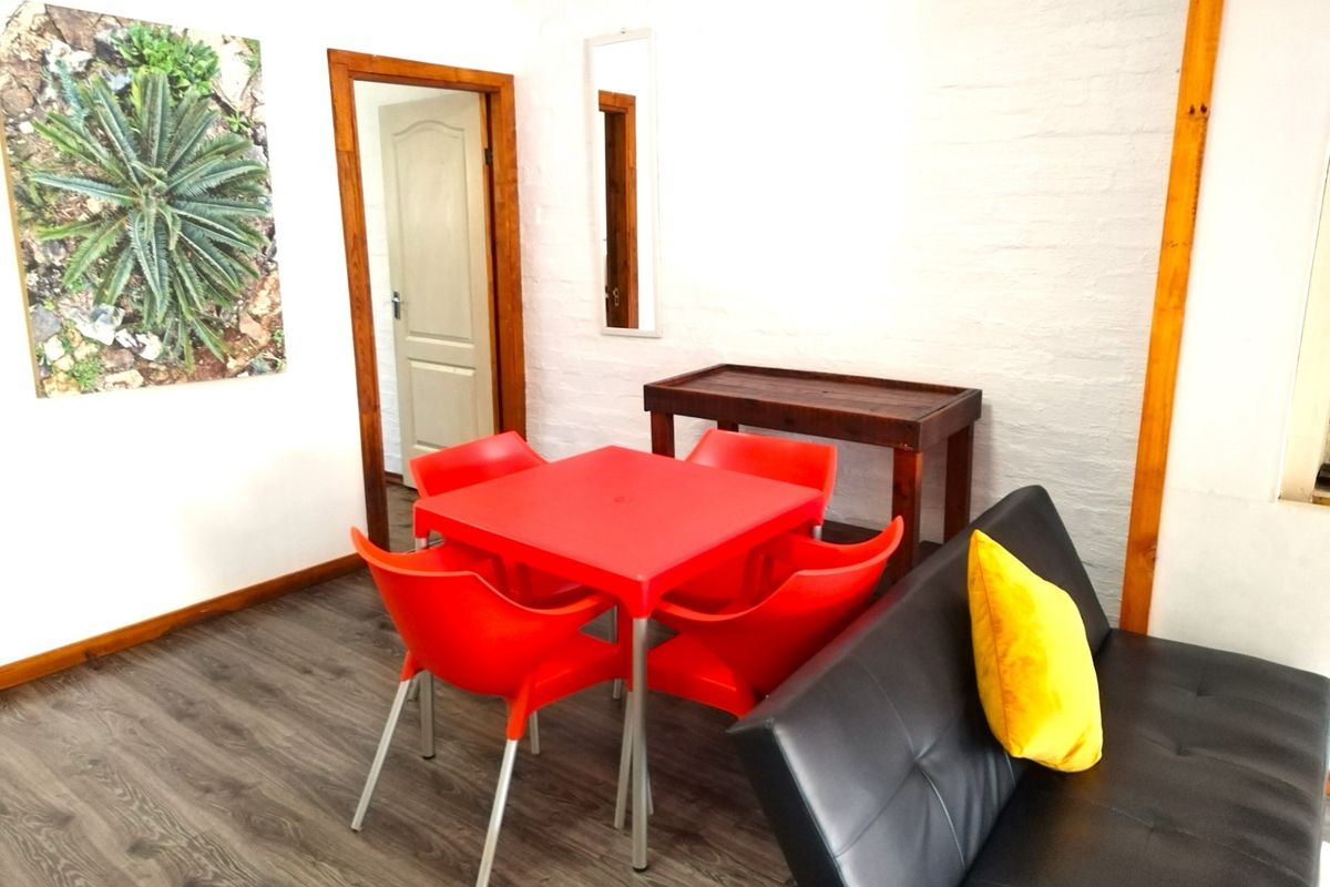 A functional living area featuring wood-look laminate flooring, white painted brick walls, and wooden door frames.
