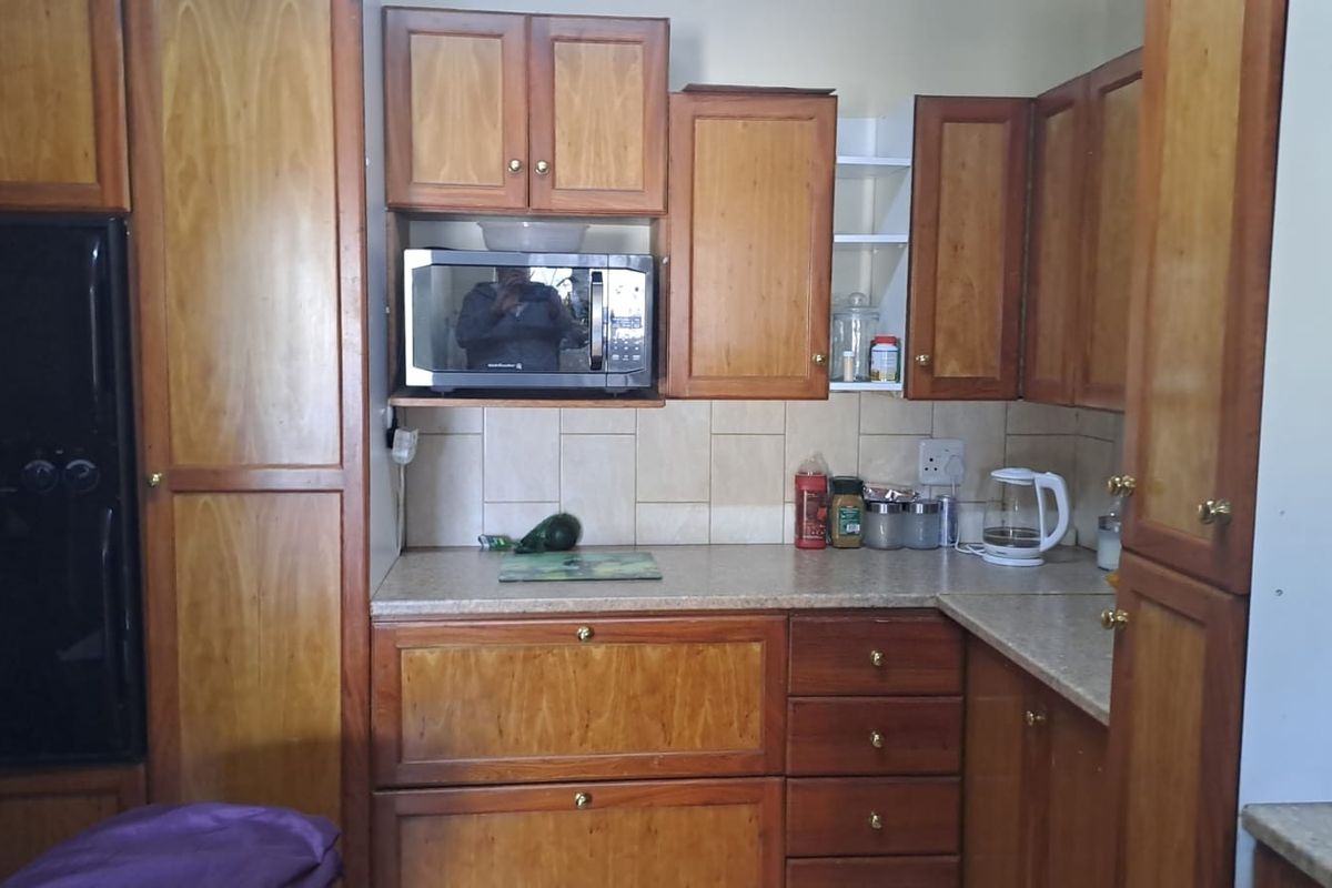 A functional kitchen featuring wooden cabinetry, laminate countertops, tiled backsplash, and a built-in microwave.