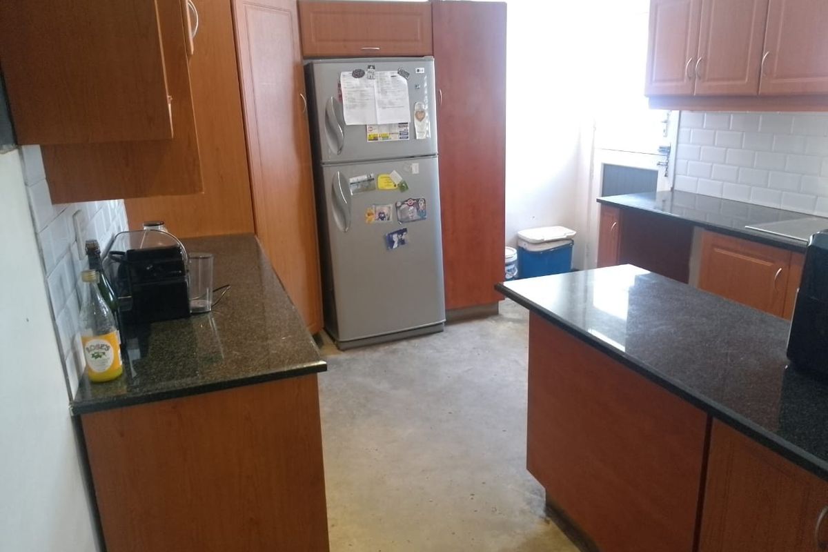 A functional kitchen featuring wood-veneer cabinetry, dark granite countertops, and a subway tile backsplash, with direct access to an exterior door.