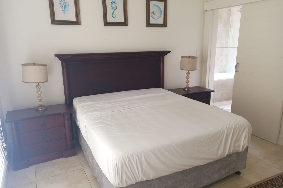 A well-maintained bedroom featuring tiled flooring and a sliding door providing direct access to an en-suite bathroom.