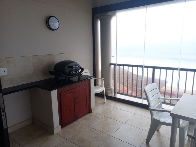 Covered balcony featuring tiled flooring, built-in cabinetry with granite countertop, and a glass enclosure offering outdoor views.