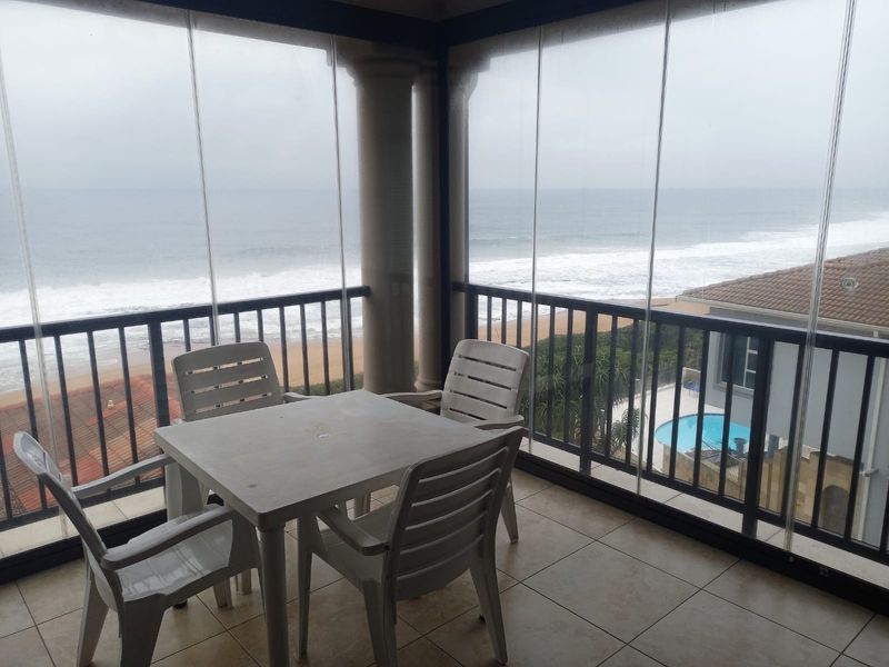 Enclosed balcony featuring tiled flooring, a metal balustrade, and expansive glass panels offering direct ocean views.
