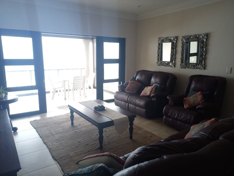 Spacious living room featuring tiled flooring, crown molding, and large sliding glass doors providing direct access to an outdoor balcony area.