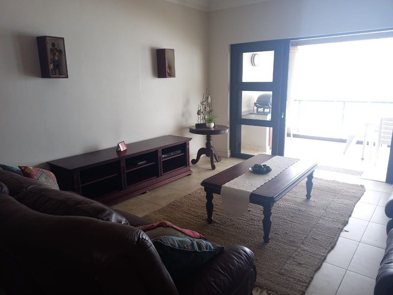 A living room featuring tiled flooring and a large sliding glass door providing access to an outdoor balcony area.