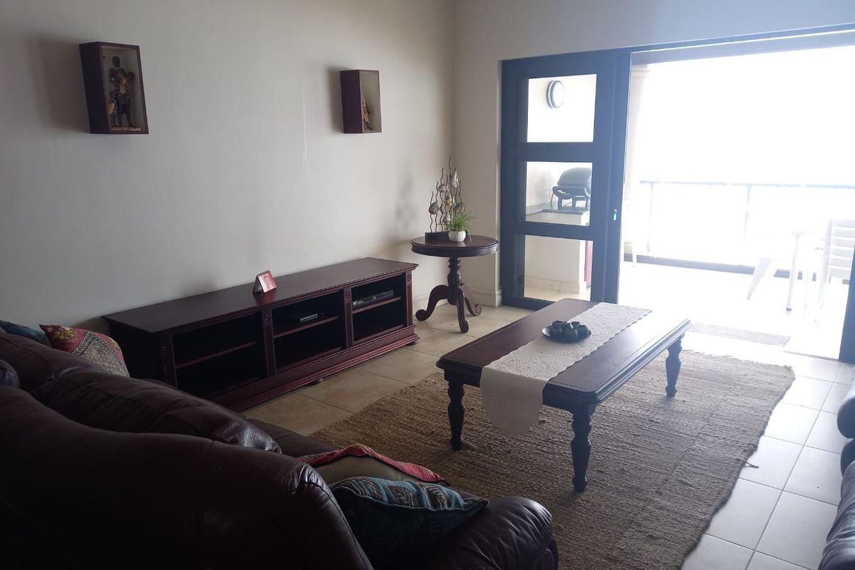 A living room featuring tiled flooring and a large sliding glass door providing access to an outdoor balcony area.
