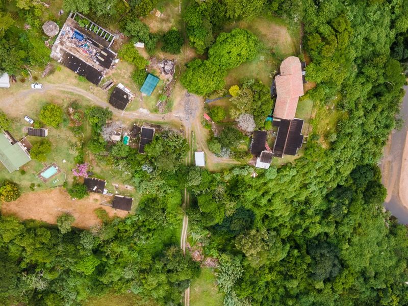 Aerial view of a commercial property complex featuring multiple structures, a swimming pool, and extensive natural surroundings with river frontage.