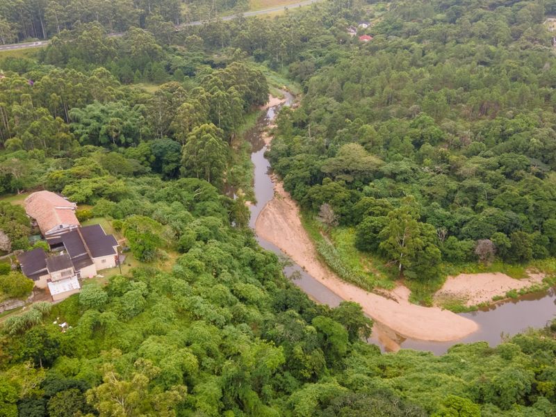An aerial view of the property situated in a lush, forested landscape adjacent to a winding river.