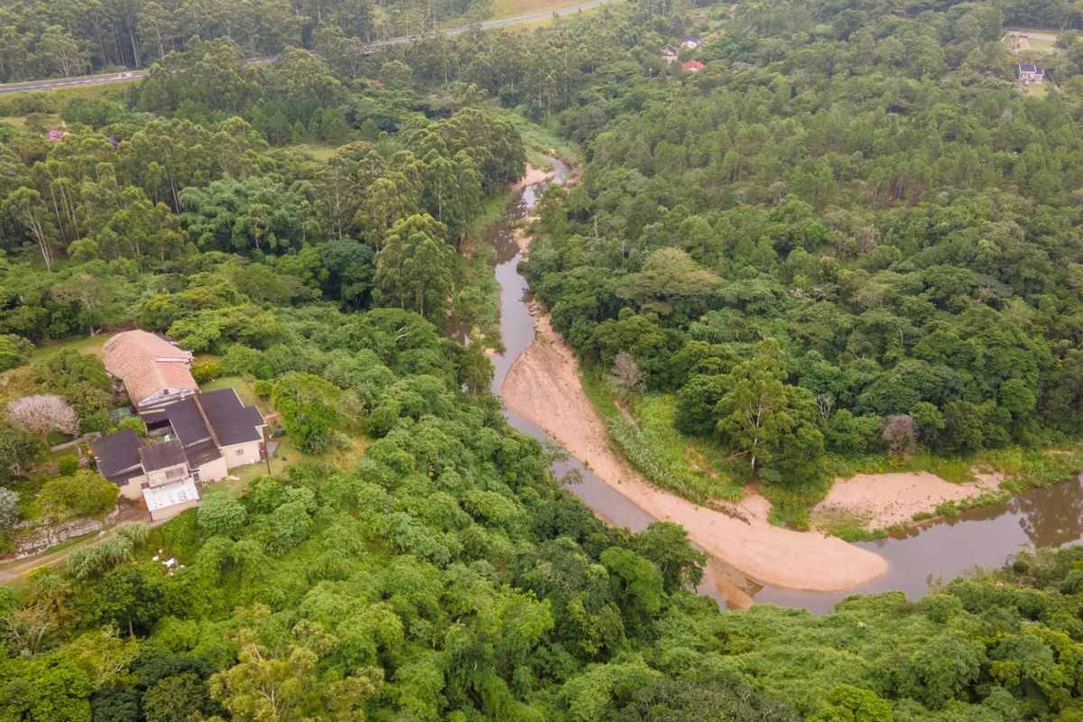 An aerial view of the property situated in a lush, forested landscape adjacent to a winding river.