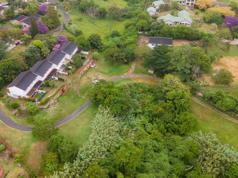 An aerial view of the commercial property grounds, showcasing the building structure, surrounding lush greenery, and access driveway.