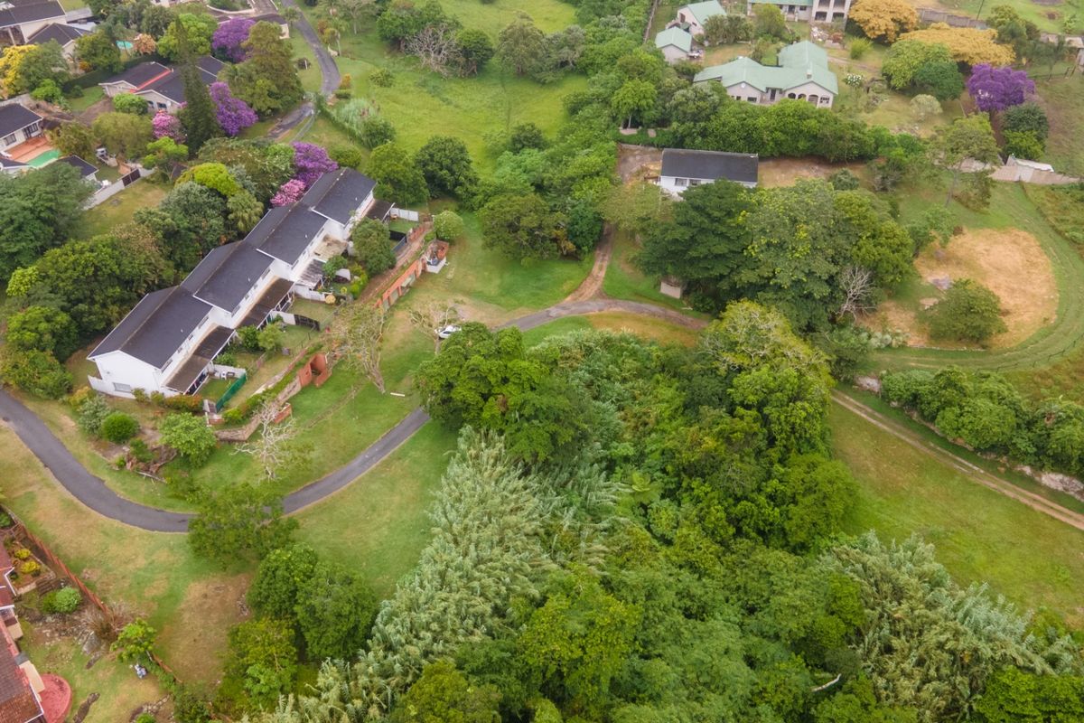 An aerial view of the commercial property grounds, showcasing the building structure, surrounding lush greenery, and access driveway.