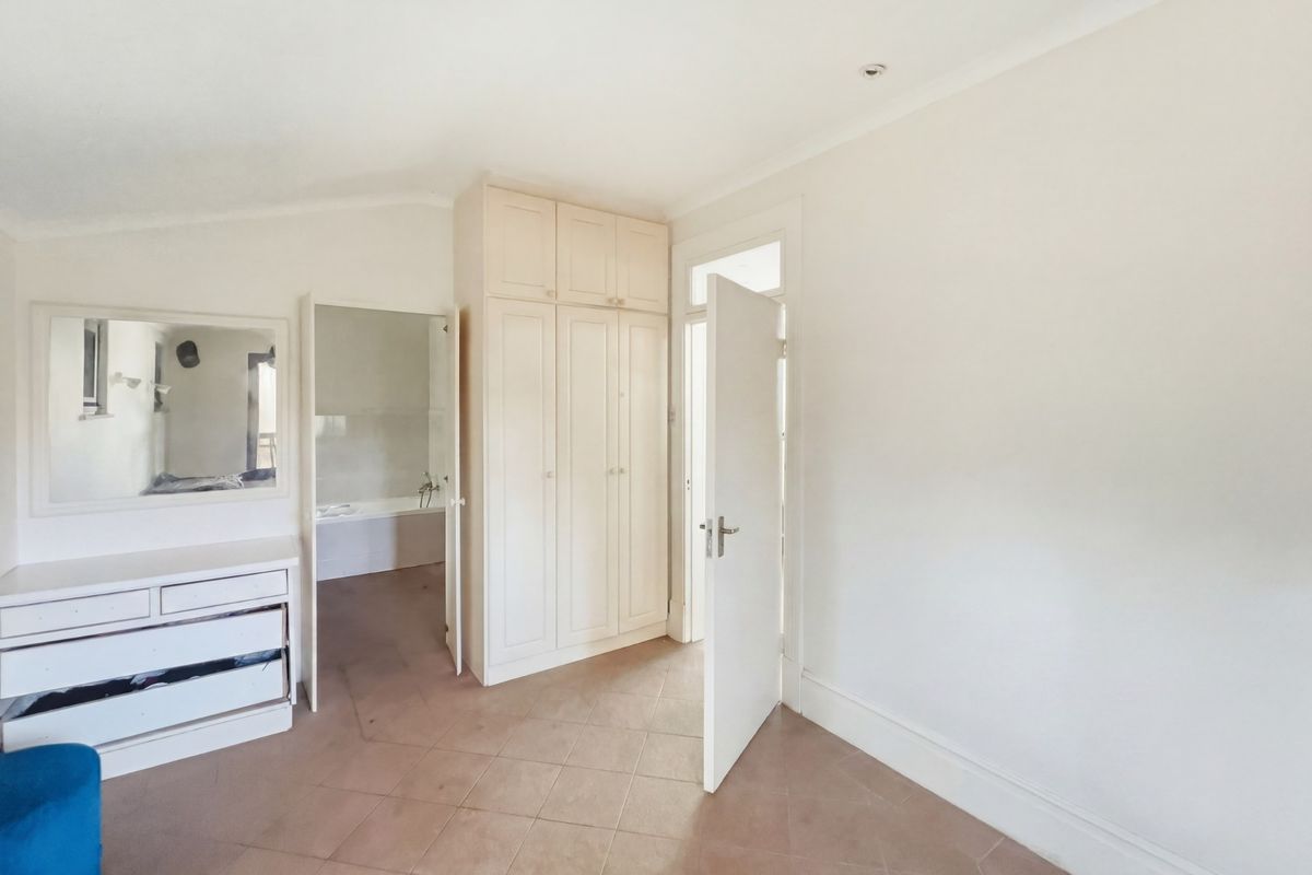 A bedroom featuring built-in cabinetry, tiled flooring, and direct access to an en-suite bathroom.