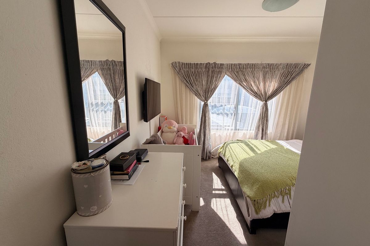 A bedroom featuring carpeted flooring, a large window with curtains, and a ceiling-mounted light fixture.