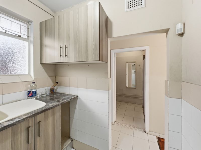 A functional scullery area featuring laminate cabinetry, an inset sink, and tiled finishes, providing a practical secondary workspace adjacent to the main living areas.