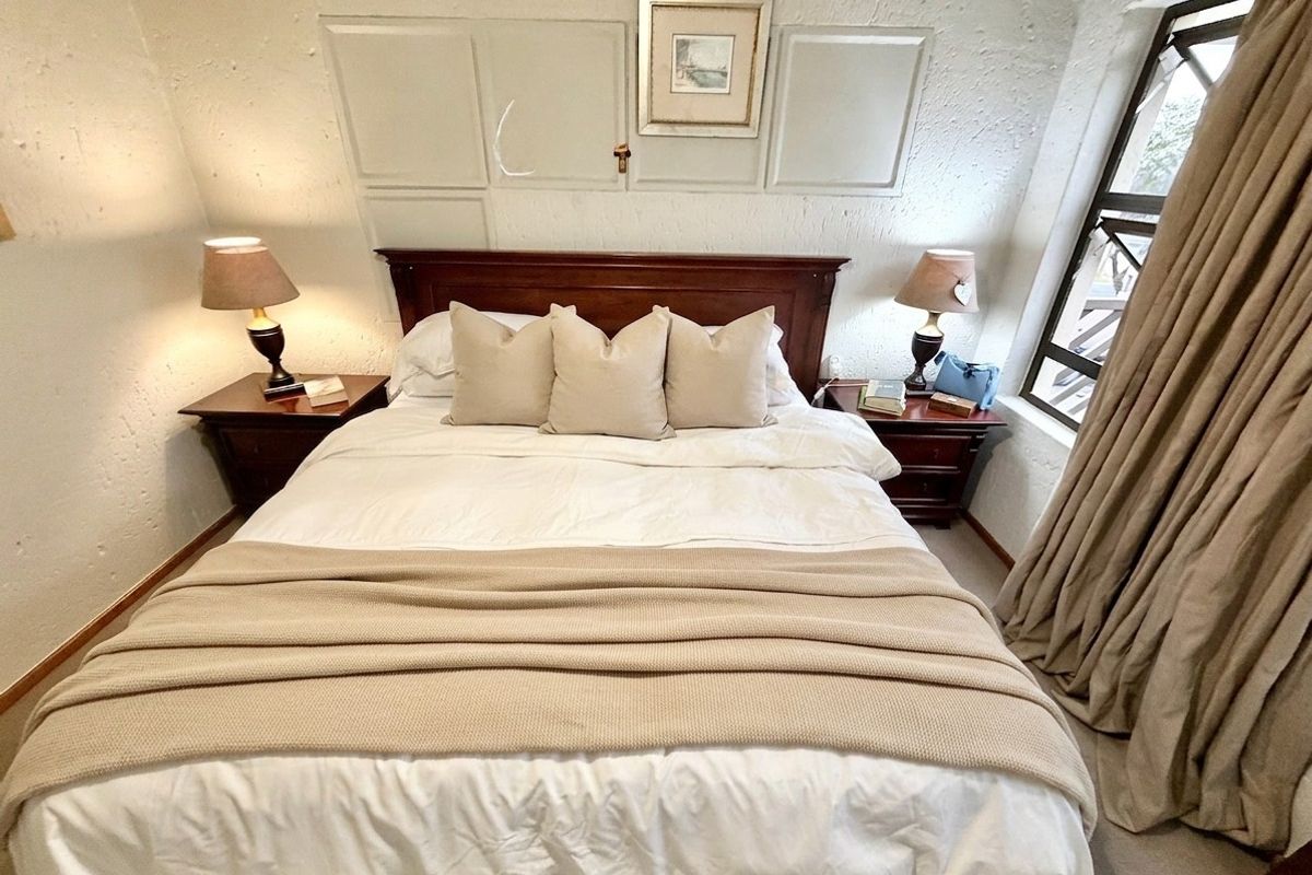 A cozy bedroom featuring textured walls and a side window with curtains, providing a comfortable and functional sleeping space.