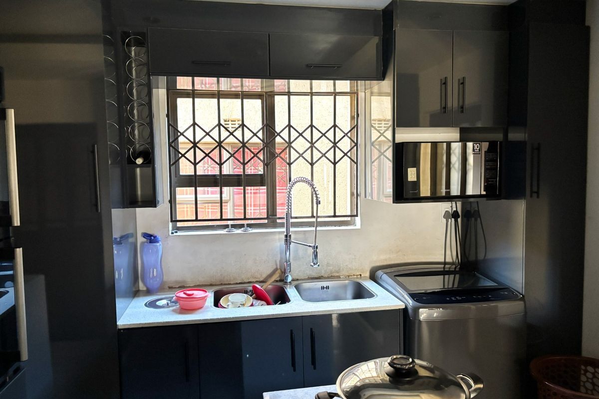 Modern kitchen featuring dark cabinetry, stone countertops, a stainless steel double sink with gooseneck faucet, and integrated microwave.