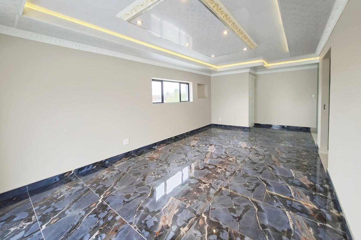 Spacious living area featuring high-gloss marble-effect floor tiles, a decorative recessed ceiling with integrated LED lighting, and neutral wall finishes.