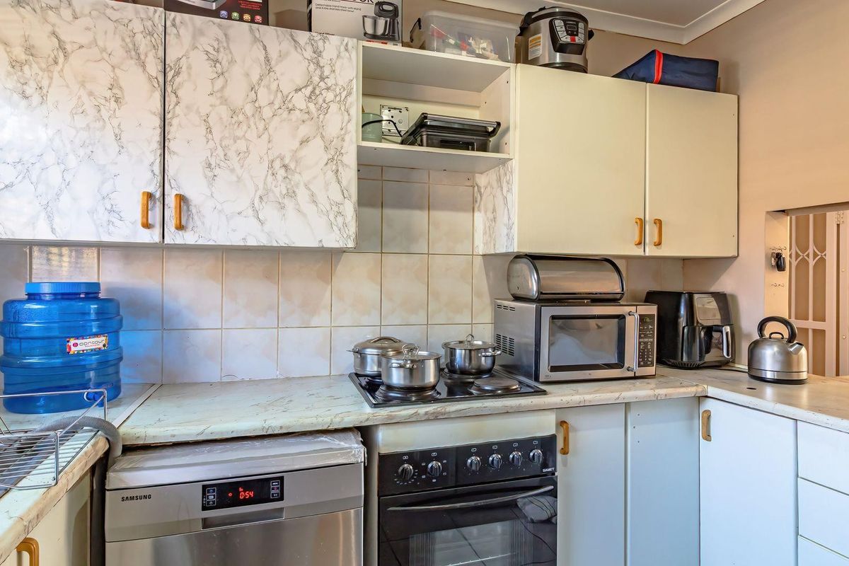 A functional kitchen featuring built-in cabinetry, a tiled splashback, and a fitted stove with oven, offering a practical layout for daily meal preparation.