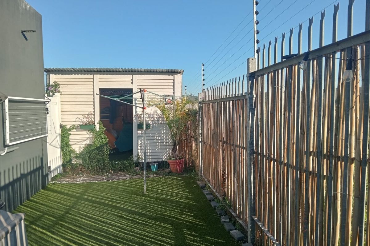 A compact rear garden area featuring artificial turf, a detached storage shed, and perimeter security fencing with electric wiring.