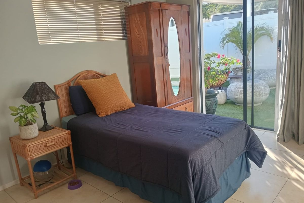 A bedroom featuring tiled flooring and large sliding glass doors that provide direct access to an outdoor patio area.