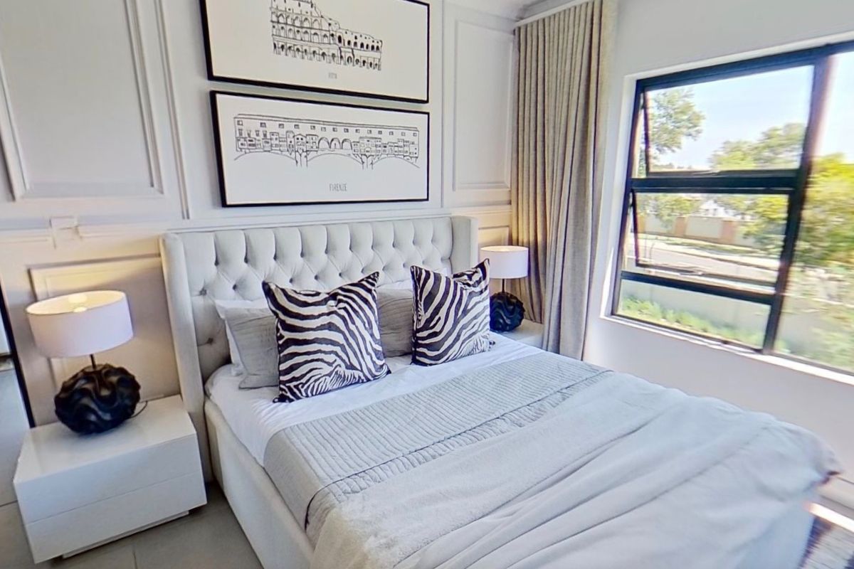 A well-appointed bedroom featuring elegant wall paneling, tiled flooring, and a large casement window providing natural light.