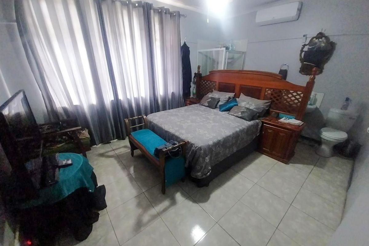 Spacious bedroom featuring ceramic floor tiles, a wall-mounted split-system air conditioner, and an integrated en-suite toilet facility.