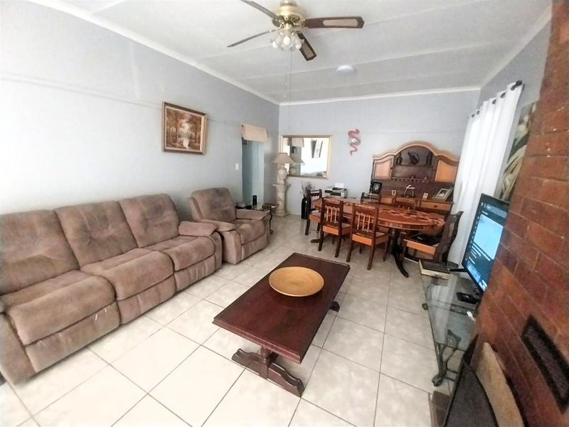Open plan living and dining area featuring tiled flooring, a brick fireplace, and a ceiling fan.