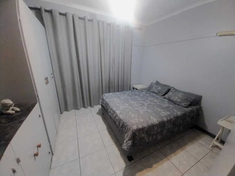 A functional bedroom featuring tiled flooring and built-in cupboards, providing a neutral base for personalization.