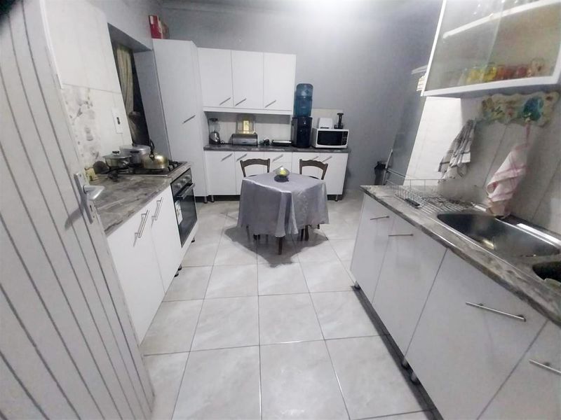 A functional kitchen featuring white cabinetry, laminate countertops, a stainless steel sink, and a built-in oven with a gas hob.