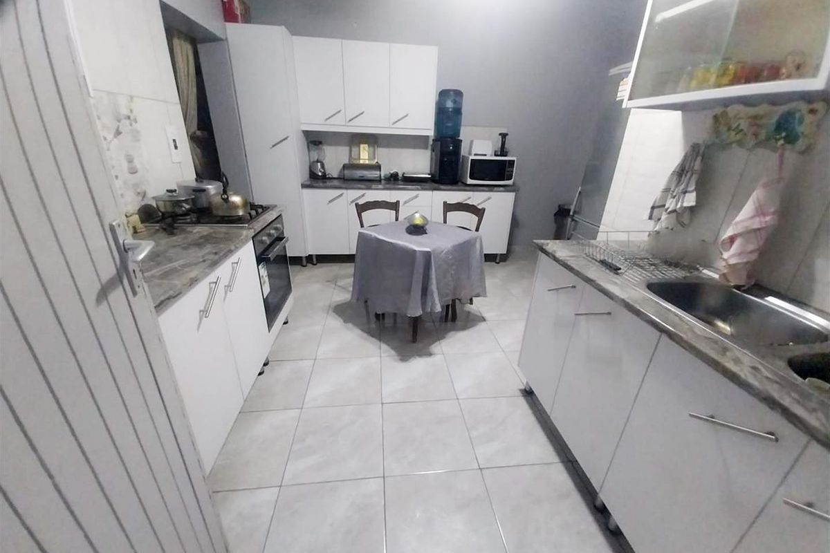 A functional kitchen featuring white cabinetry, laminate countertops, a stainless steel sink, and a built-in oven with a gas hob.