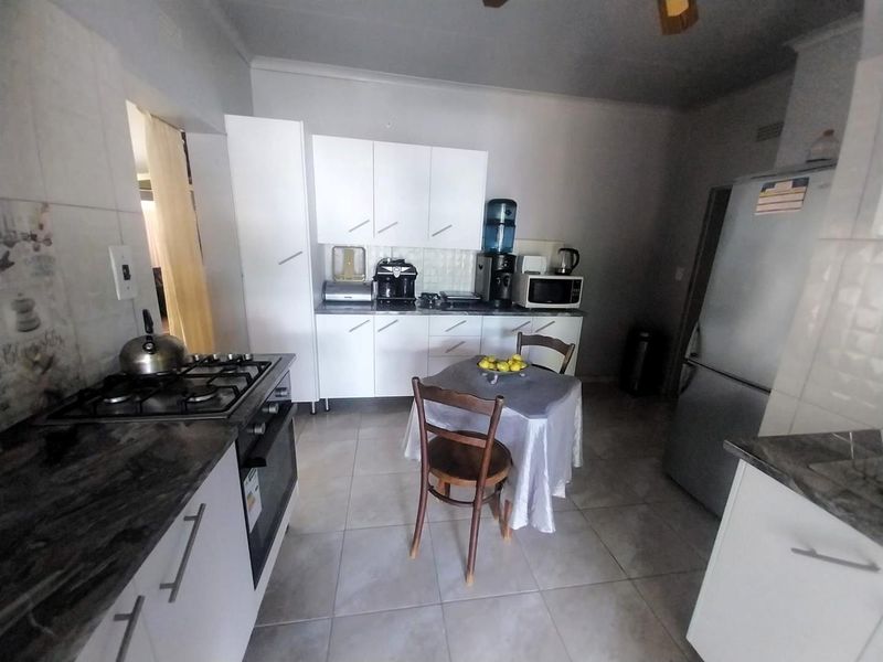 A functional kitchen featuring white cabinetry, dark countertops, a gas hob, and an integrated oven, with tiled flooring throughout.