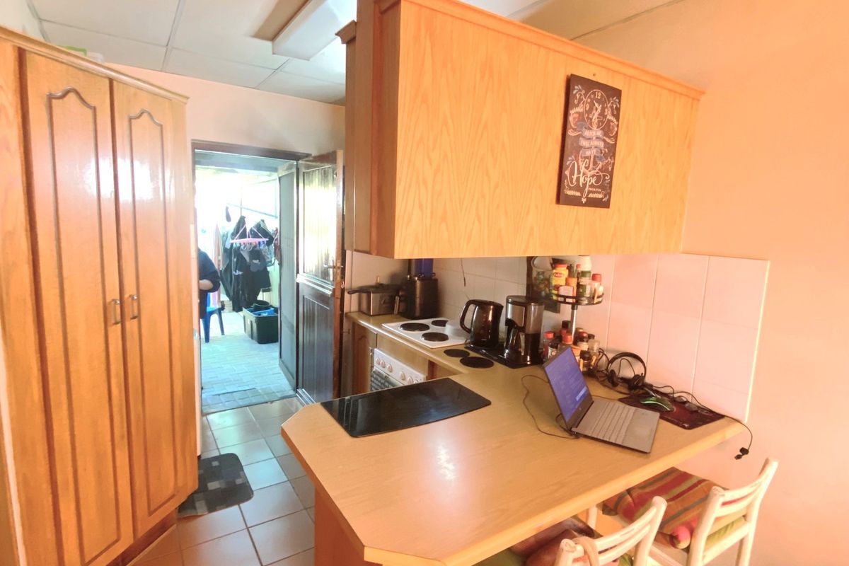A functional kitchen area featuring wooden cabinetry, a built-in hob, and a breakfast counter, with direct access to an outdoor area.