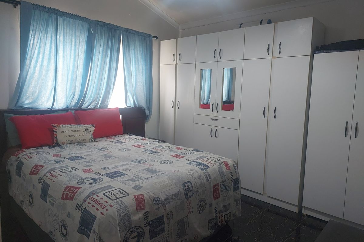 A bedroom featuring built-in white cabinetry and tiled flooring, providing ample storage space.