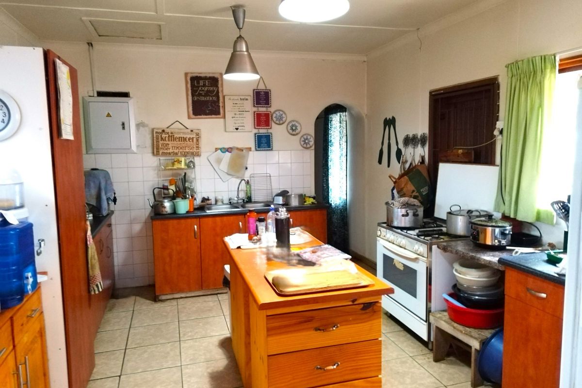 A functional kitchen featuring wooden cabinetry, a central island, tiled flooring, and a freestanding gas stove with an integrated oven.