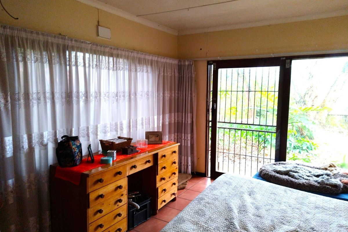 A bedroom featuring tiled flooring, large windows with curtains, and a security gate leading to the garden area.