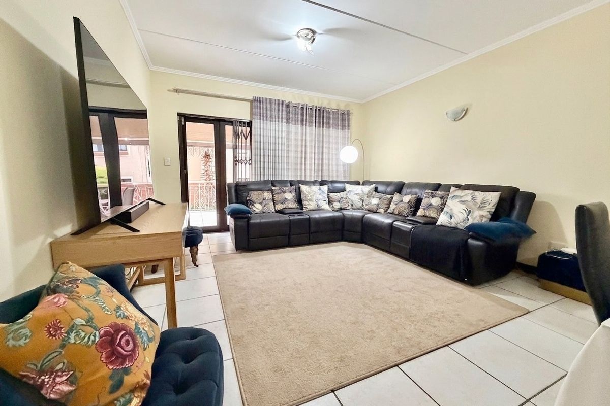 A spacious living room featuring tiled flooring, a coved ceiling, and a sliding glass door providing access to an outdoor area.