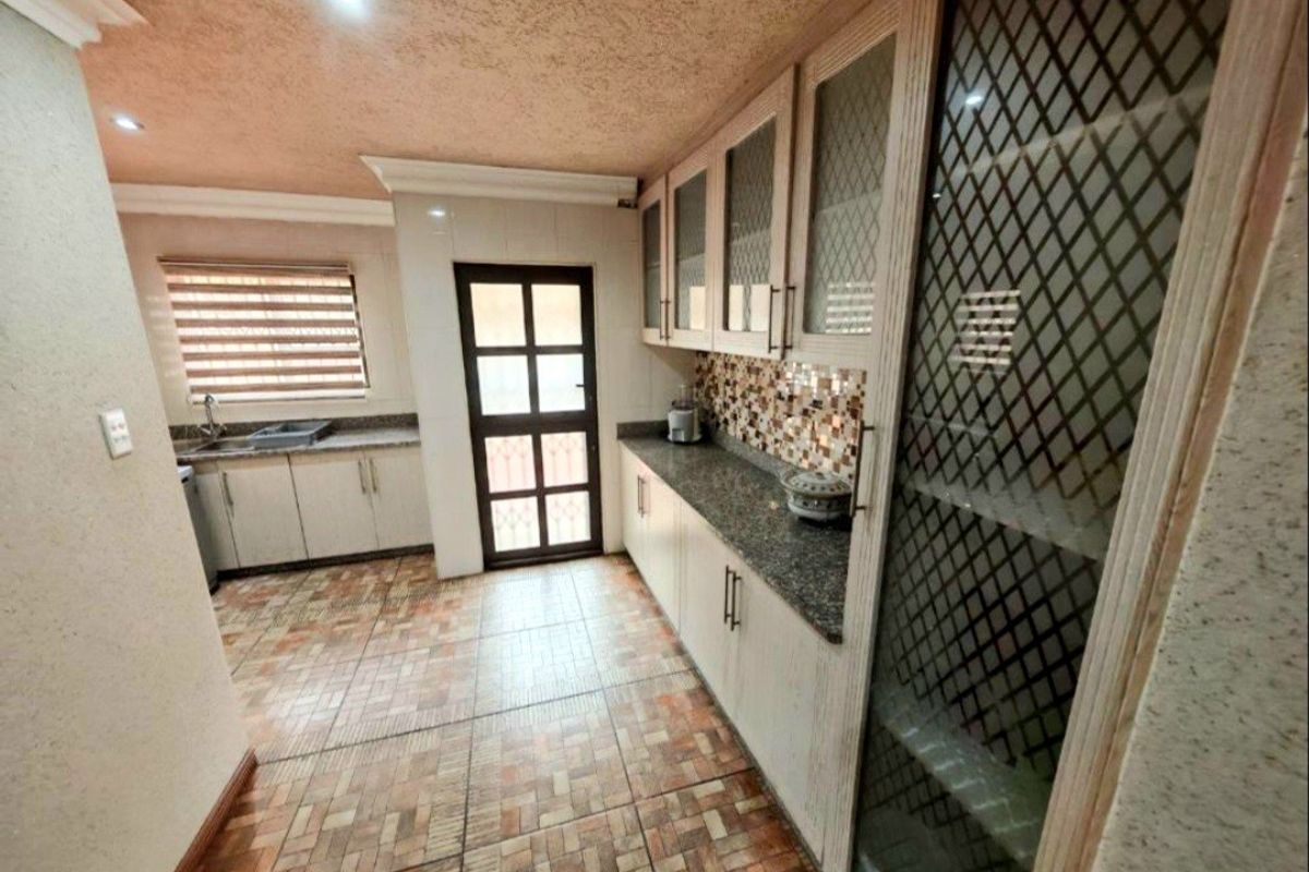 A functional kitchen featuring built-in cabinetry, granite countertops, mosaic tile backsplash, and direct access to an exterior door.