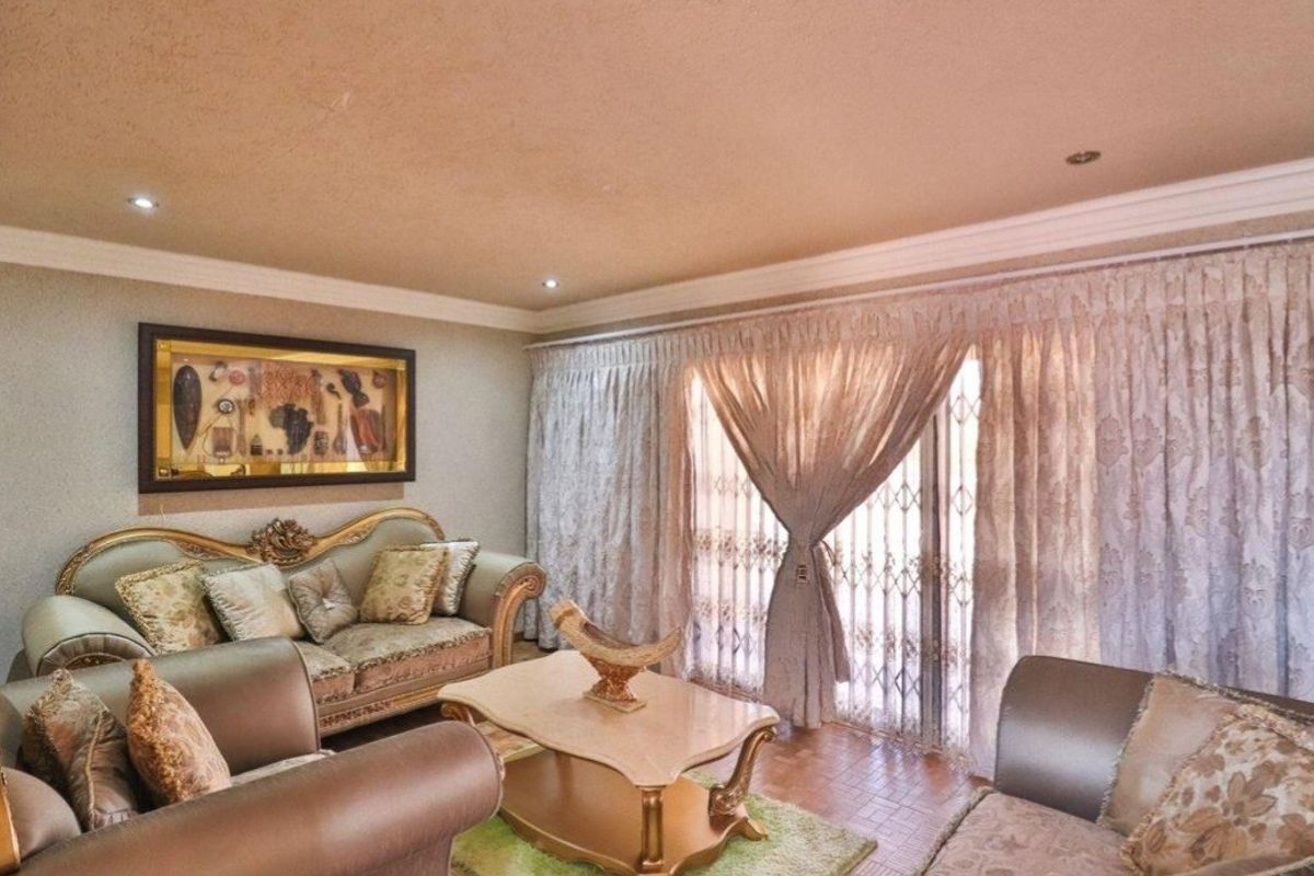 A comfortable living room featuring recessed ceiling lighting, crown molding, and large sliding glass doors with security gates leading to the exterior.