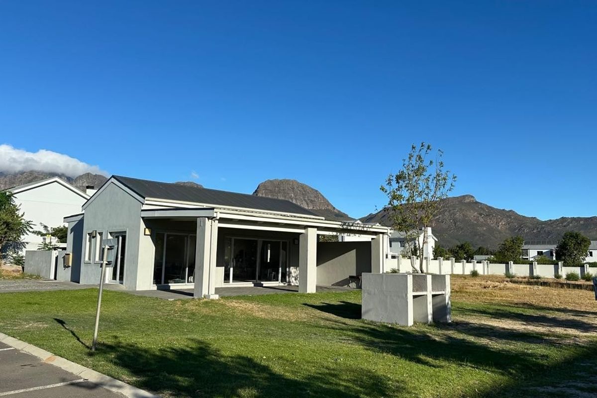 Exterior view of a modern apartment building featuring a covered patio area, built-in outdoor braai, and scenic mountain views.