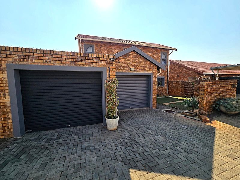 A well-maintained double garage with roller shutter doors and paved driveway, featuring face-brick exterior finishes.