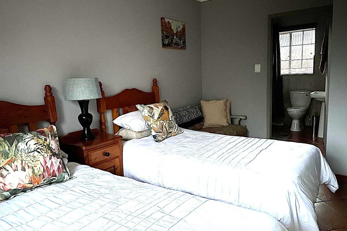 A bedroom featuring tiled flooring and an en-suite bathroom with a toilet and pedestal basin.