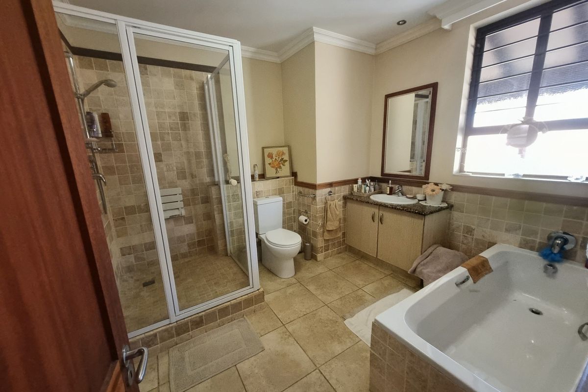 Spacious bathroom featuring a separate glass-enclosed shower, built-in bathtub, vanity with stone countertop, and neutral tiled finishes.