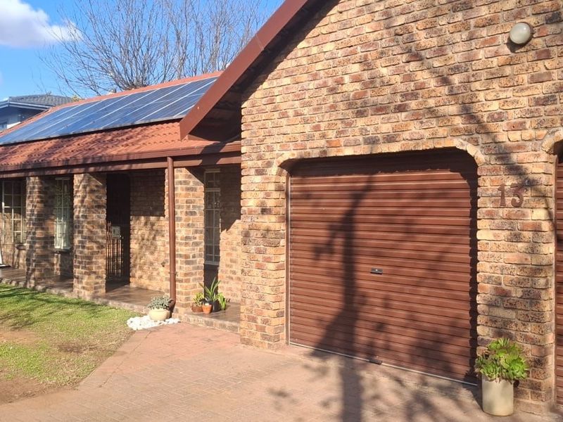 Front exterior view of a face-brick house featuring double garages, a covered entrance porch, and roof-mounted solar panels.
