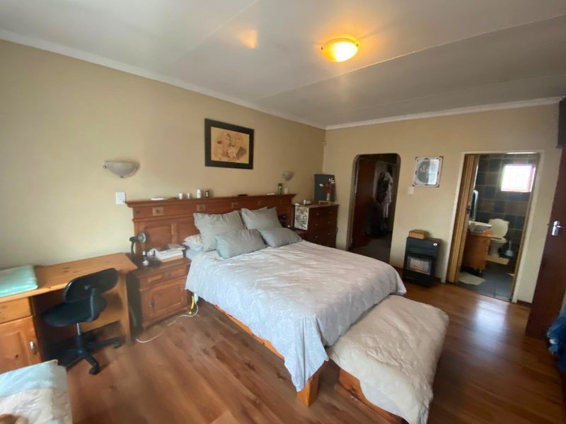 A bedroom featuring laminate wood flooring, built-in headboard, and an en-suite bathroom access.