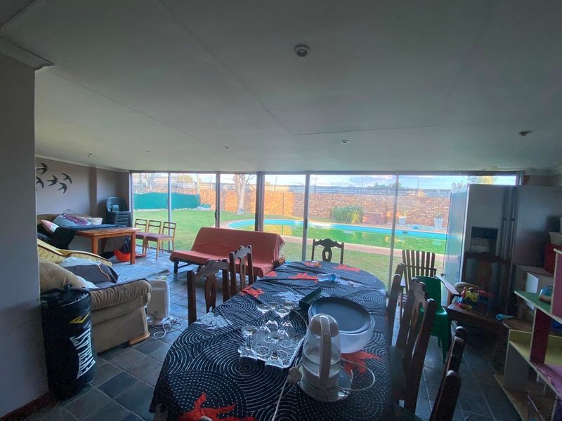 Spacious open-plan living and dining area featuring large sliding glass doors that provide direct access to the rear garden and swimming pool.
