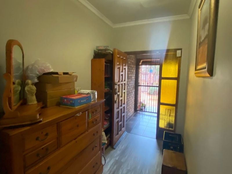 A functional hallway featuring wood-look flooring, crown molding, and a secure entrance door with decorative glass panels.