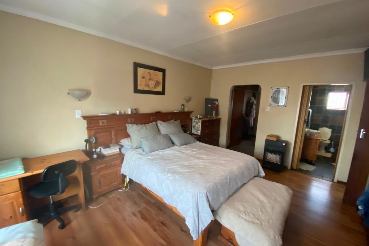 A bedroom featuring laminate wood flooring, built-in headboard, and an en-suite bathroom access.