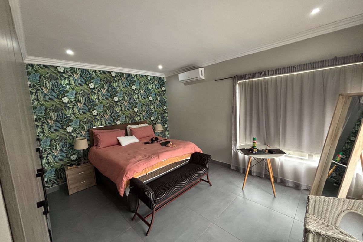 Spacious bedroom featuring tiled flooring, recessed downlighting, air conditioning, and a decorative feature wall with built-in cupboard storage.