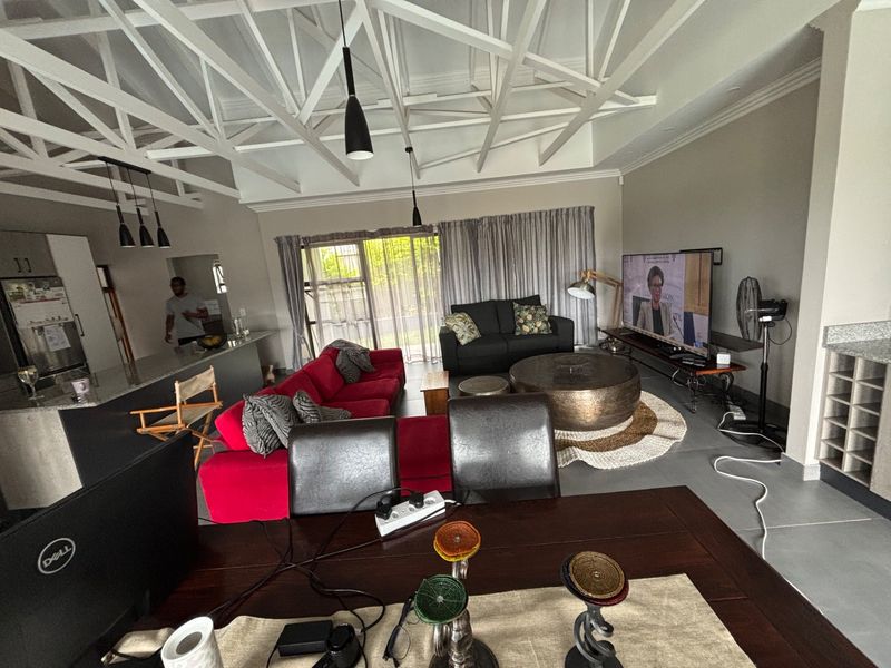 Spacious open-plan living area featuring exposed white roof trusses, a modern kitchen island with granite countertops, and large sliding doors leading to the exterior.