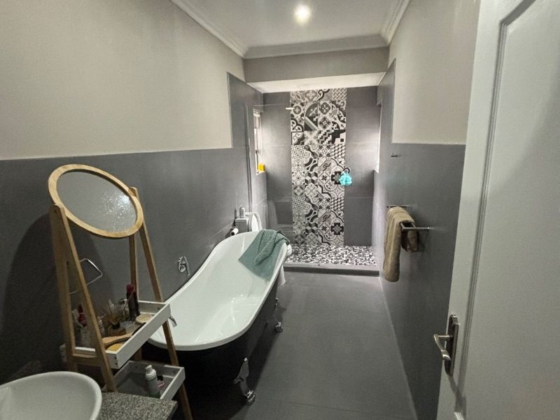 Modern bathroom featuring a freestanding bathtub, a walk-in shower with decorative patterned tiling, and a vanity with a vessel sink.