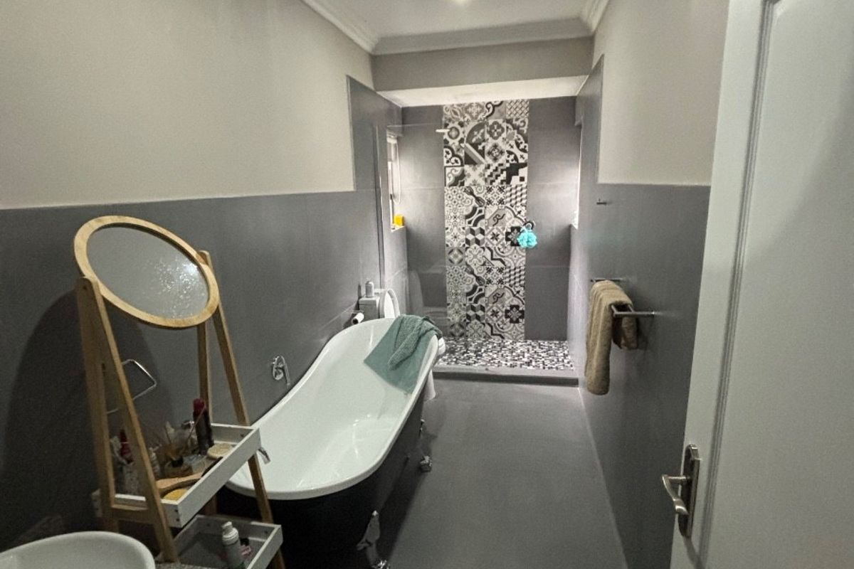 Modern bathroom featuring a freestanding bathtub, a walk-in shower with decorative patterned tiling, and a vanity with a vessel sink.